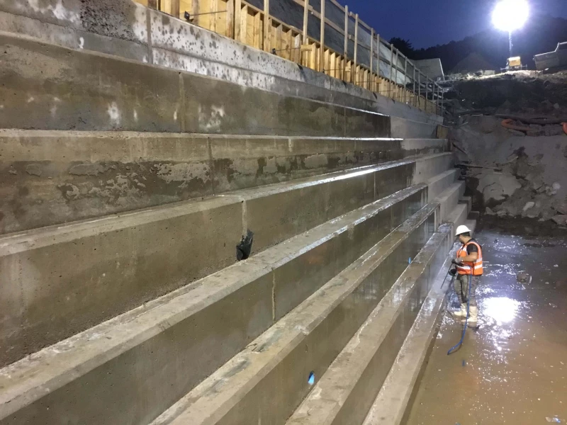 Photo was taken of crem member finishing the face of the RCC following striping of temporary falsework.  This project consisted of lowering the lake, excavation of the down stream toe of the dam and installation of a new toe buttress and new 10 wide doweled face, constructed from High Slump RCC.