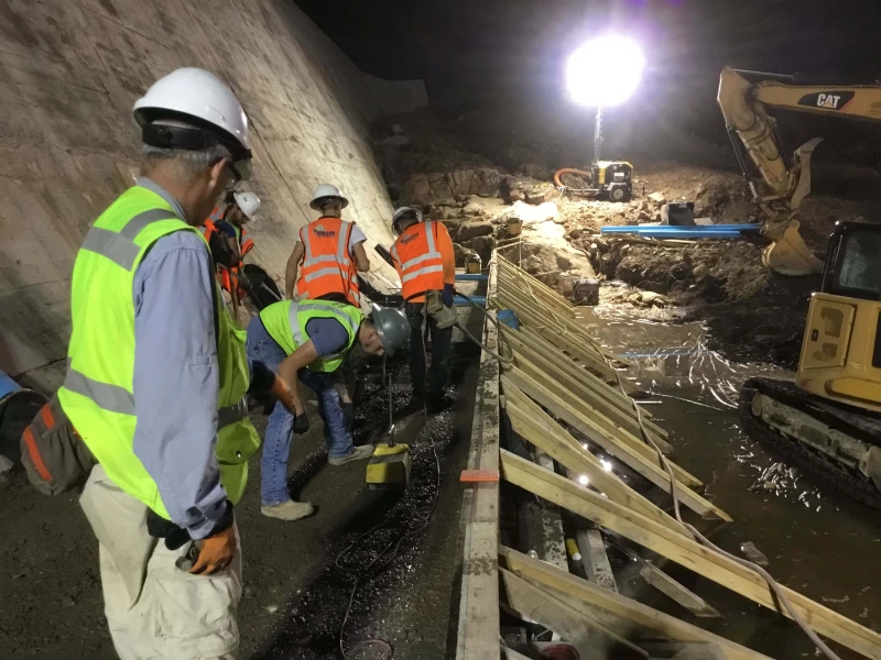 Photo was taken of crem members and inspectors Placing and Testing RCC on the new face of the Dam,  This mix is considered a wet RCC Face Requiring forming to help hold it in place.