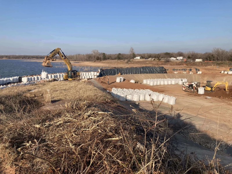 This photo is taken during the construction of temporary cofferdam used to hold back the lake during construction.  This project consisted of construction of Temp Cofferdam, Bypass Pumping, Demolition of Existing Spillway, Installation of Rock Anchors, Subsurface Piping, and Pouring of Cutoff Walls, Slabs and New Spillway Walls.