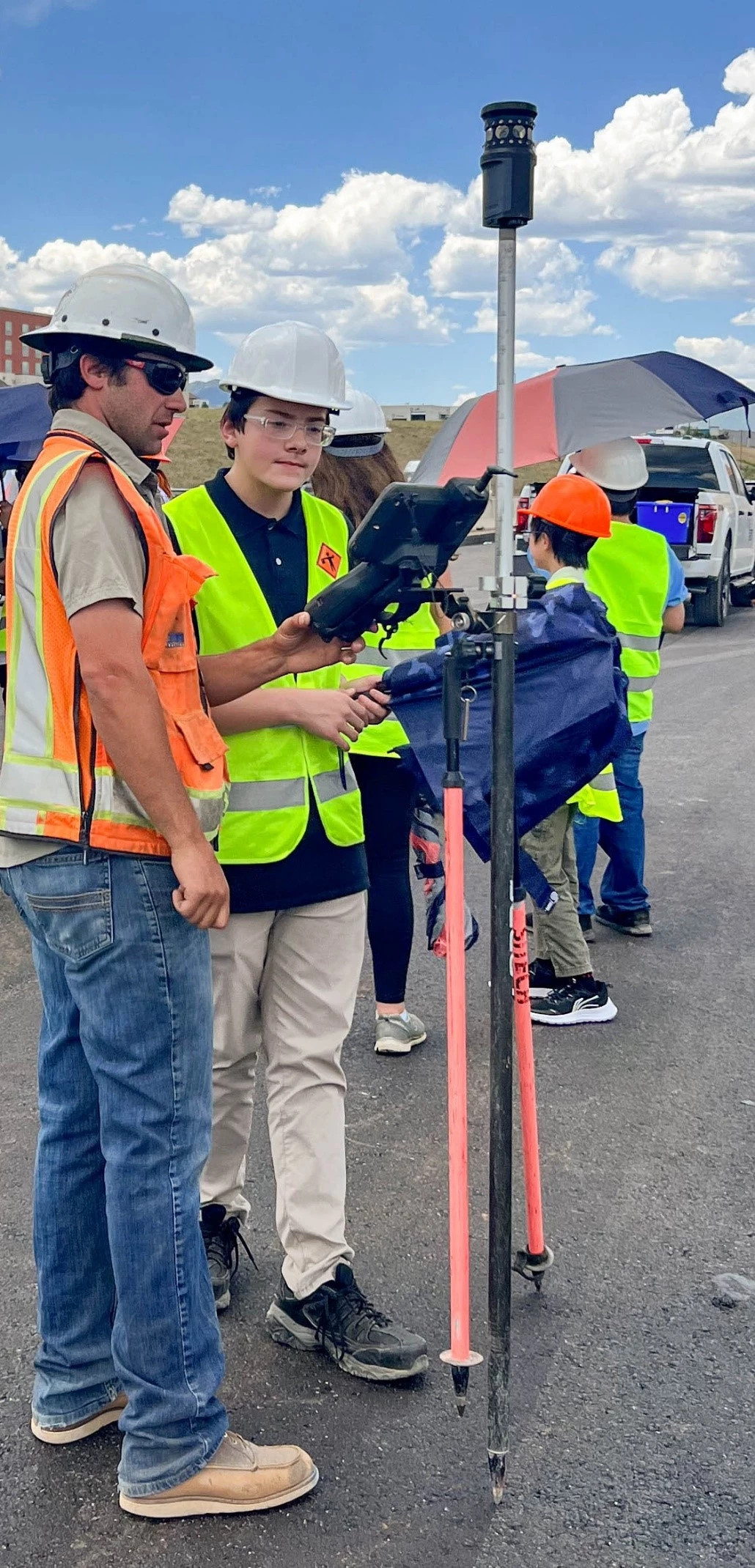 A SEMA team member and a NIST student hold a piece of survey equipment.
